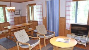 A cozy room with a wooden dining table, two chairs, a small TV, and a window with curtains.