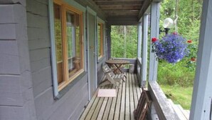A wooden deck with a covered porch, a table, and chairs.
