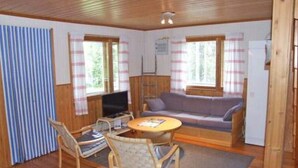 A cozy room with a wooden floor, a sofa, a television, and a table with chairs.