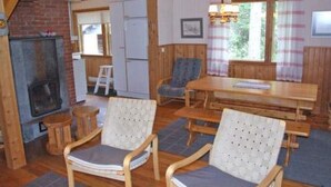A cozy cabin interior with a fireplace, wooden furniture, and a dining area.