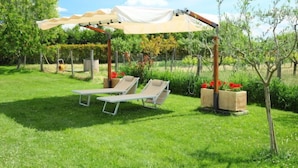 A covered outdoor seating area with two lounge chairs and a pergola structure.