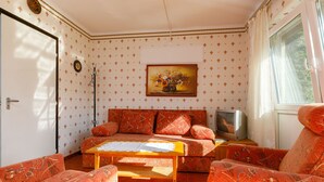 Ein Zimmer mit einer Sofagarnitur, einem Tisch und einem Fernseher.