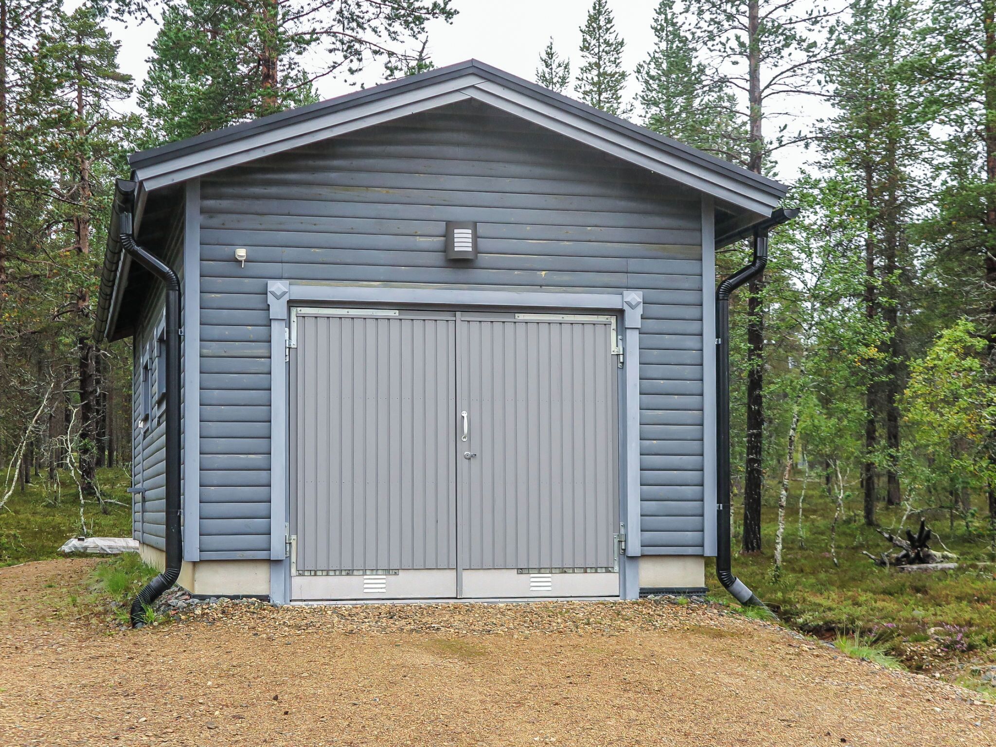 A single-story building with a large garage door, surrounded by a forested area.