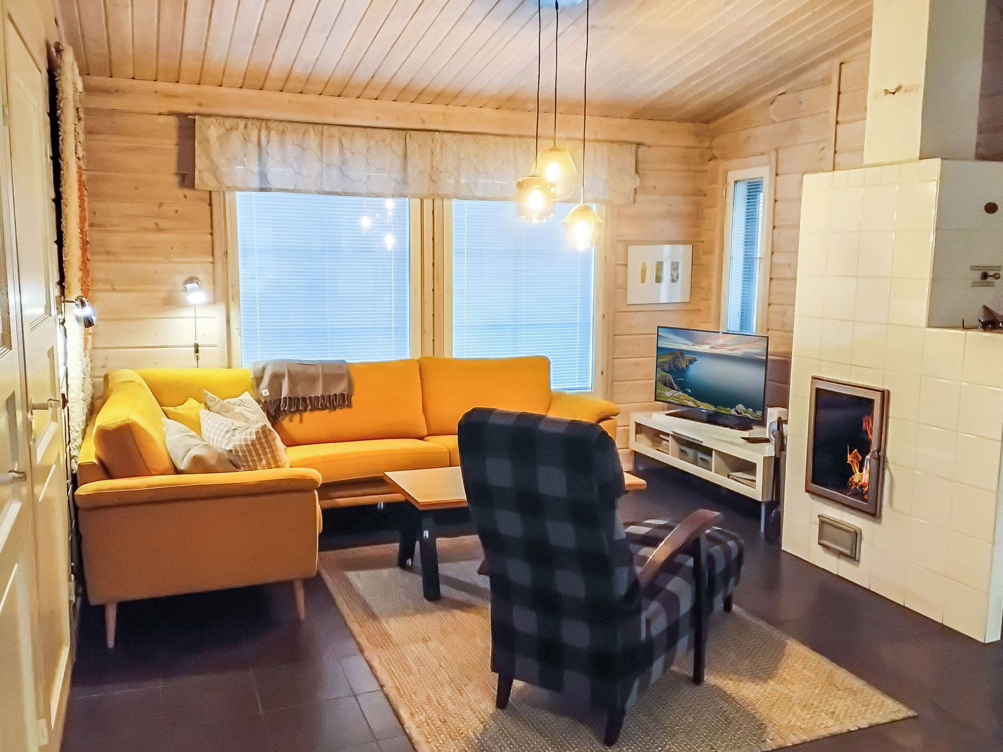 Ein gemütliches Wohnzimmer mit einer Couch, einem Sessel, einem Fernseher, einem Kamin und Holzwänden.