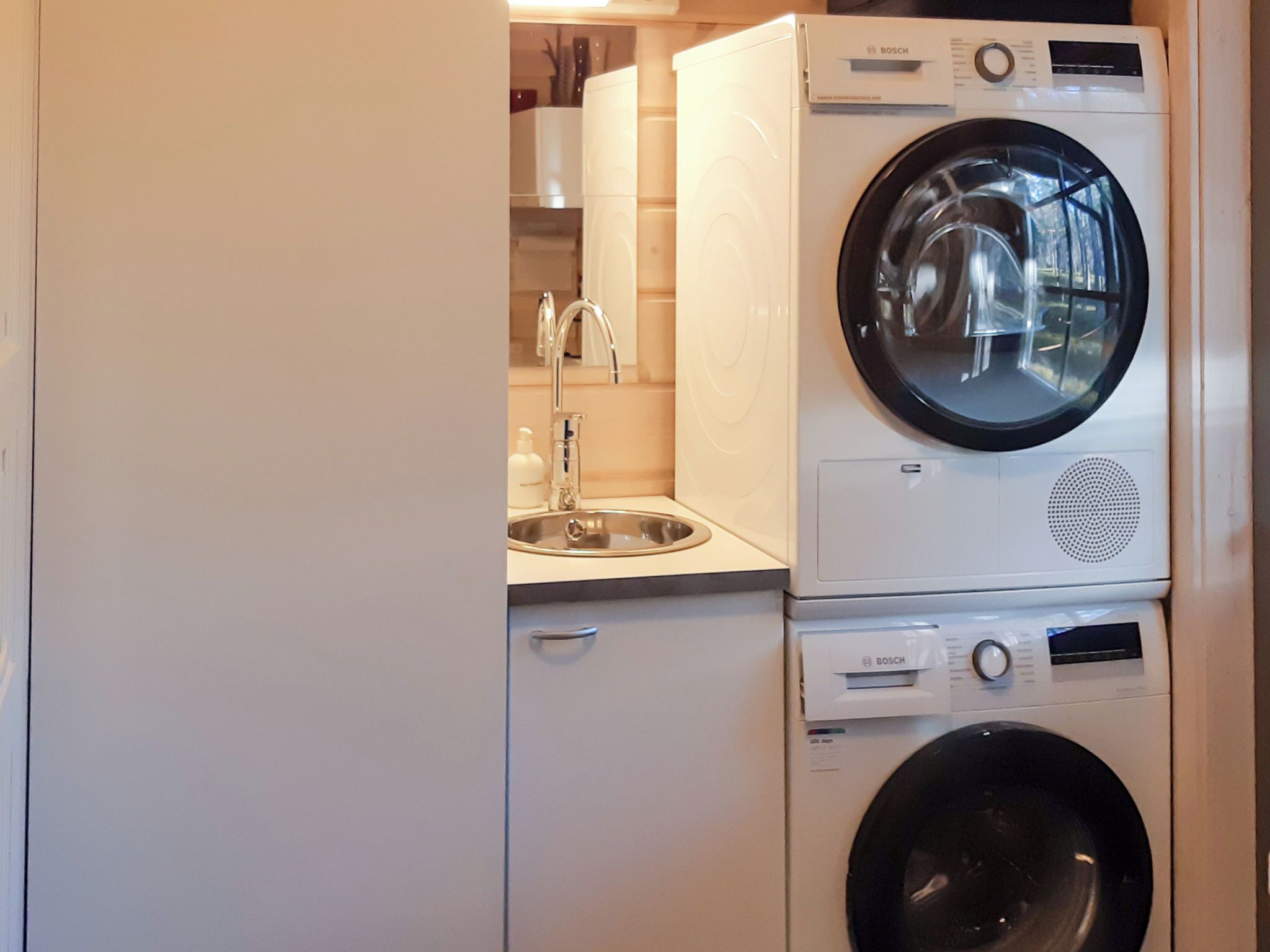 A compact laundry area with a Bosch washing machine and dryer stacked on top of each other.