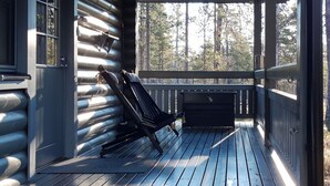 Una terraza de madera con una silla lounge negra y un calentador exterior negro.