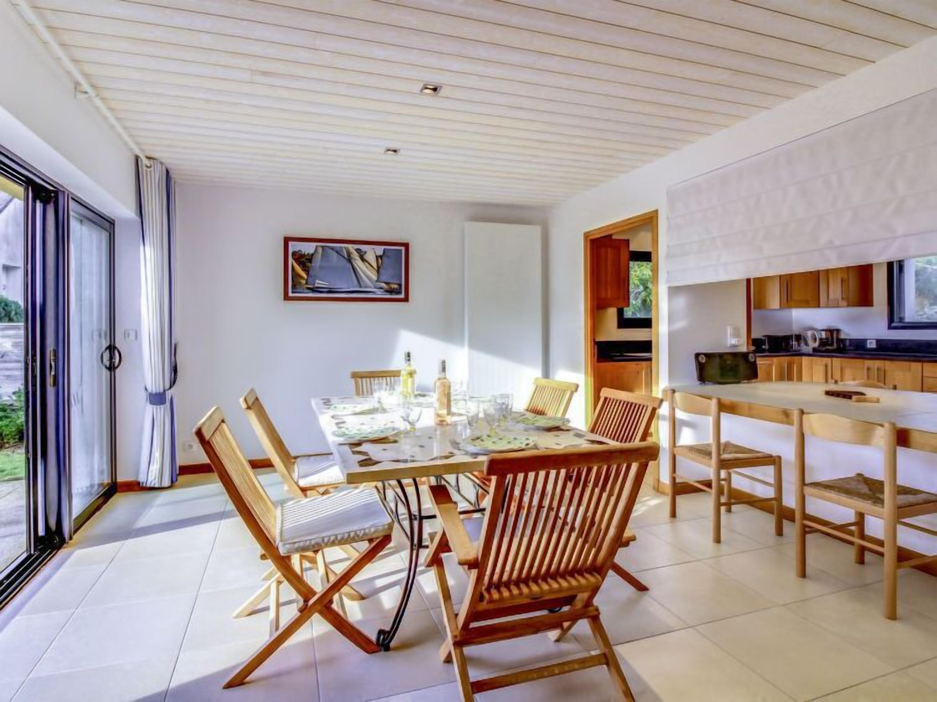 A dining area with a table set for four, surrounded by wooden chairs.