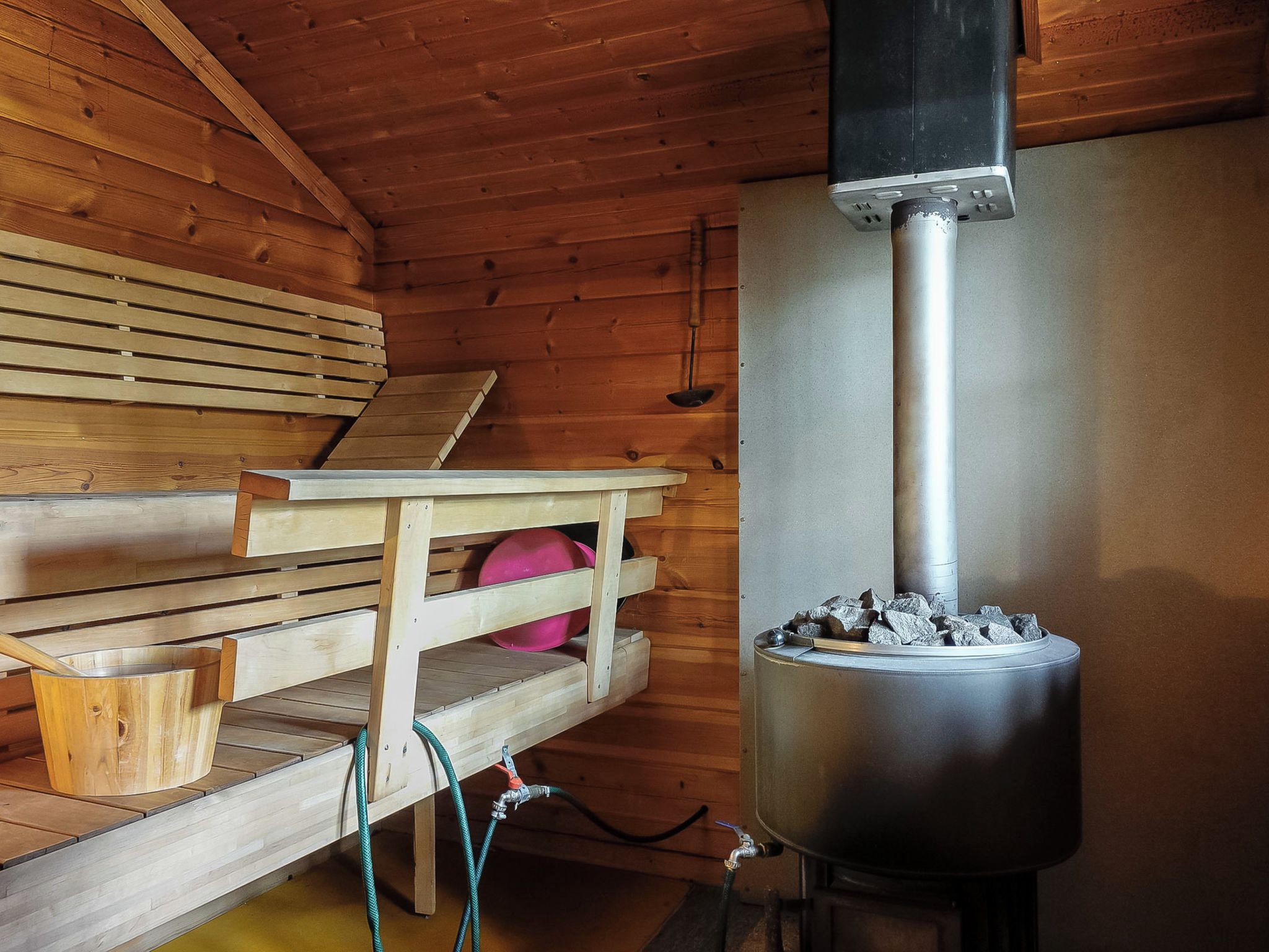 Una sauna con panche in legno, un tavolo e un'unità sauna con pietre.