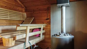 Een sauna met houten banken, een tafel en een sauna-unit met stenen.