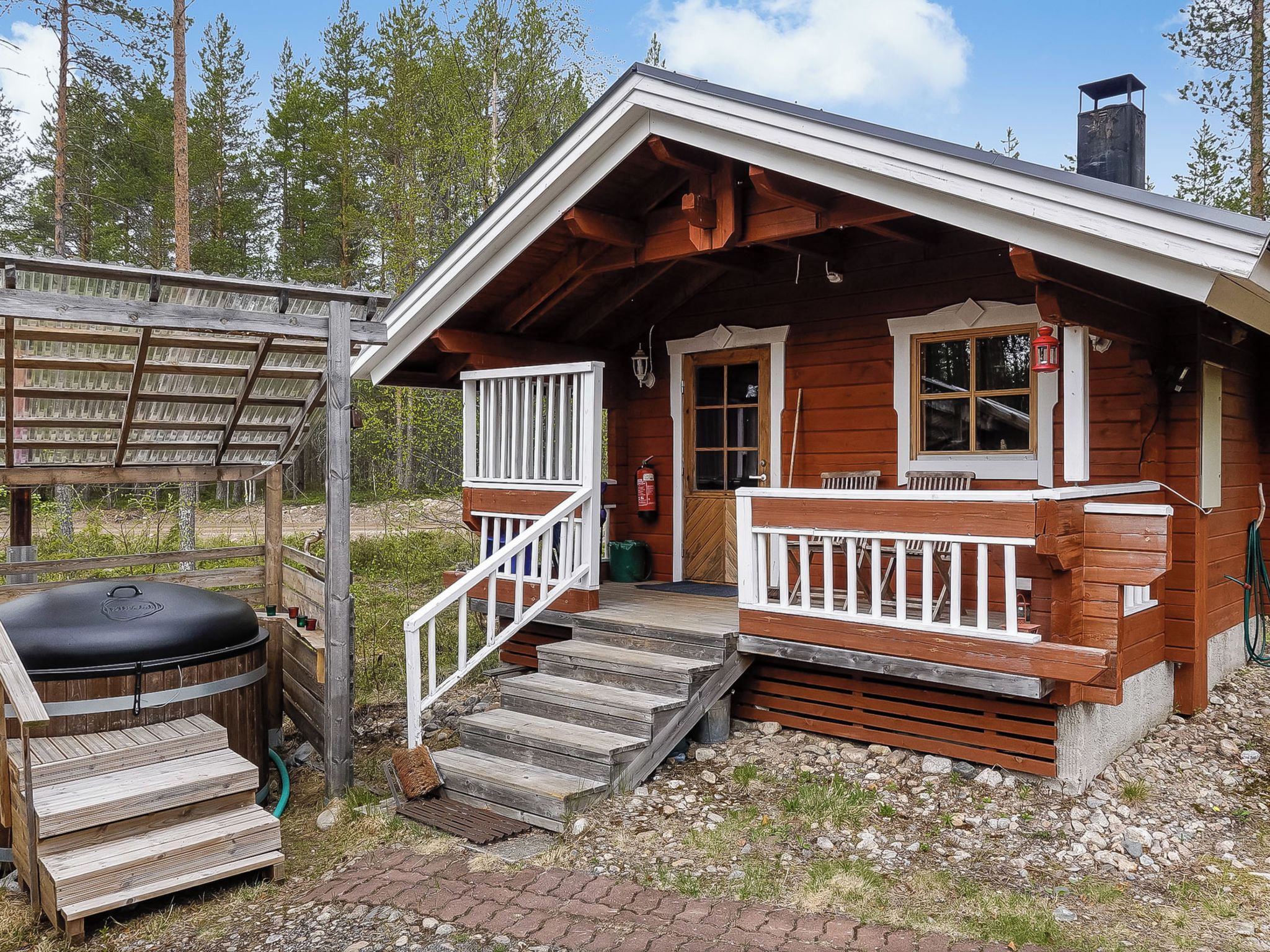 A wooden cabin with a porch, steps, and a grill area.
