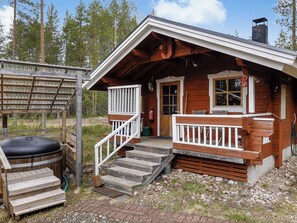 A wooden cabin with a porch, steps, and a grill area.