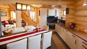 Acogedor interior de cabaña de madera con comedor, cocina y sala de estar.