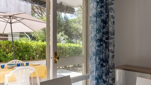 A room with a sliding glass door leading to an outdoor area with a table, chairs, and an umbrella. - Casa Polipo by Interhome (Grosseto)