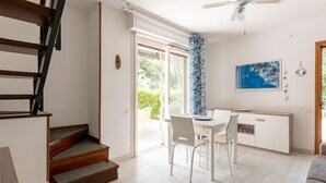 A modern kitchen with white cabinets, a dining table, and chairs. There is a staircase leading to another level. - Casa Polipo by Interhome (Grosseto)