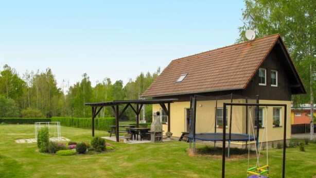 A house with a covered patio, a trampoline, and a well-maintained lawn.