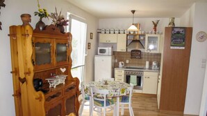 A compact kitchen with a dining area, wooden cabinets, a microwave, and a stove.