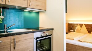 A compact kitchen with wooden cabinets, a stainless steel oven, and a teal backsplash.