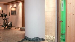 A hotel lobby with a large white pillar, exercise equipment, and a green glass door.