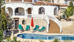 Une villa à deux étages, dotée d’une façade en pierre, d’un escalier en colimaçon et d’une piscine.