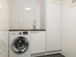 Ein kleiner Waschraum mit einer Frontlader-Waschmaschine, einem Waschbecken und einem Schrank.