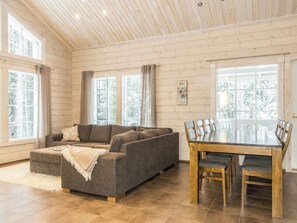 A cozy living room with a sofa, ottoman, and a dining table with chairs.