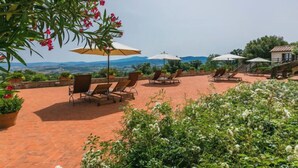 Un patio con sillones de descanso y sombrillas, con vistas a un paisaje pintoresco.