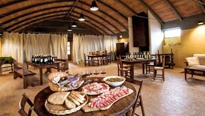 Un comedor rústico con mesas y sillas de madera, y una variedad de alimentos y bebidas.