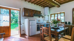Una cocina con armarios de madera, un refrigerador blanco y una zona de comedor con sillas y una mesa de madera.