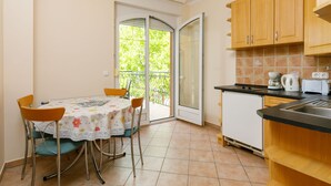 A compact kitchen with a dining area, a sliding glass door to a balcony, and basic amenities. - Lakefront 2 by Interhome (Balatonlelle)