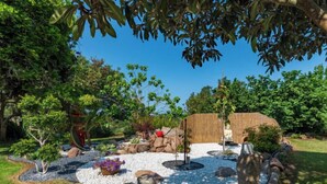 Un jardin aménagé avec une fontaine centrale, entouré de rochers et de plantes.