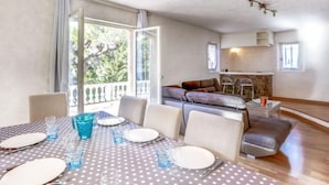 Un coin repas avec une table dressée pour quatre personnes, un canapé et, au fond, un espace cuisine.