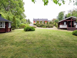 A residential property with a well-maintained lawn, a red house, and a wooden cabin.