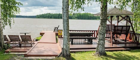A lakeside deck with wooden benches and a gazebo.