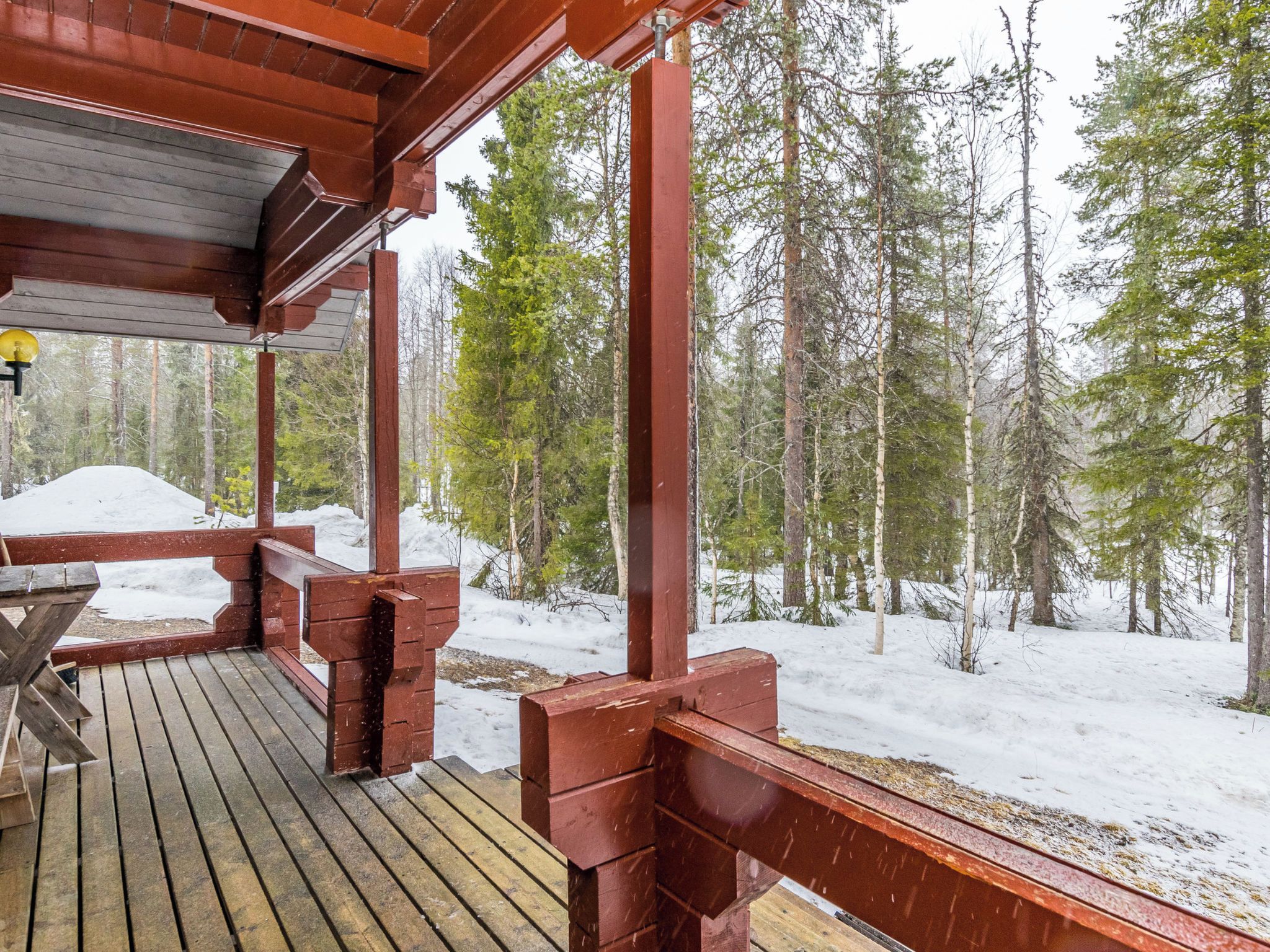 A wooden deck with a view of a snowy forest.