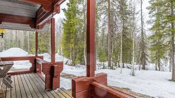 A wooden deck with a view of a snowy forest.