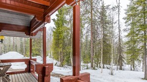 A wooden deck with a view of a snowy forest.