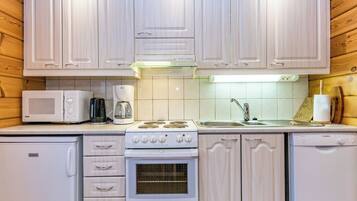 A compact kitchen with white cabinetry, a Bosch coffee maker, a microwave, a stove, and a dishwasher.