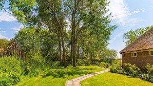 Un jardin bien entretenu, avec un chemin de pierres menant à un bâtiment en briques.