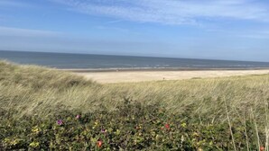 Une plage avec des dunes et un ciel dégagé.
