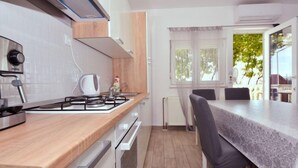 Ett modernt kök med en gasspis, en vattenkokare och en matplats med ett bord och stolar.