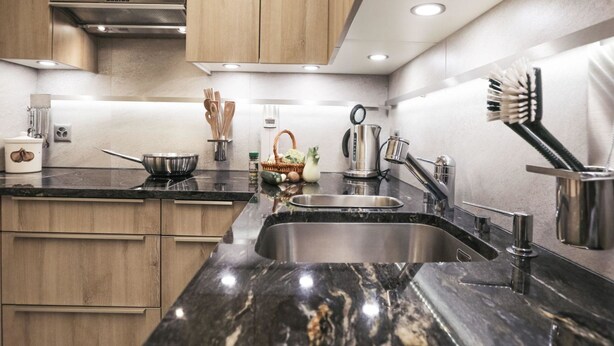 Een moderne keuken met houten kastjes, een zwarte marmeren aanrecht, roestvrijstalen apparatuur en een ingebouwd spoelbak.