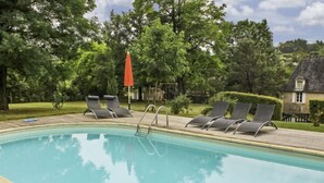 Una piscina con sillas de descanso y una sombrilla.