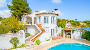 Una casa de dos pisos con piscina, mobiliario exterior y un jardín.