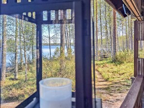 En hytte med udsigt over skov og sø.