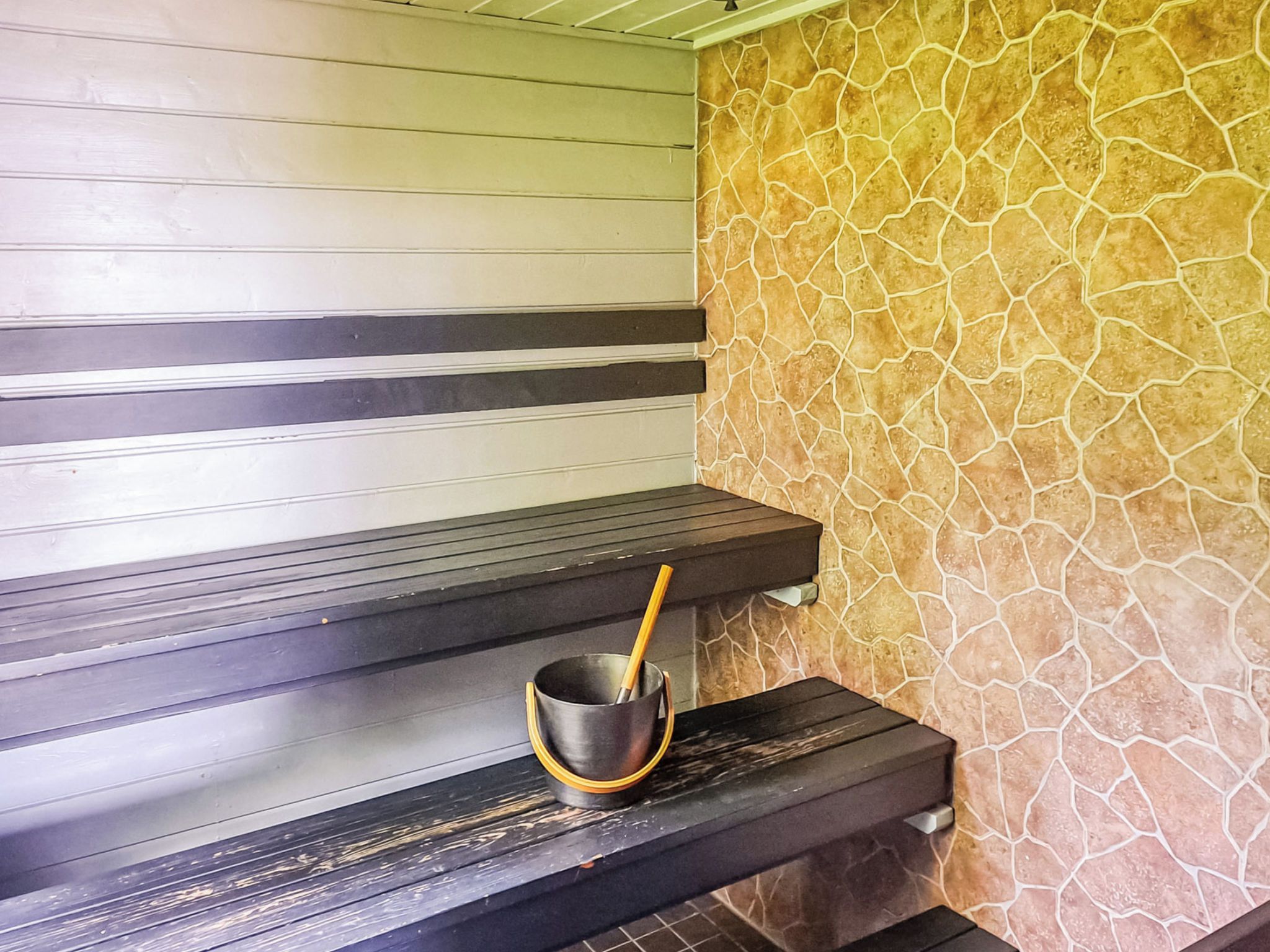 Een sauna met houten banken en een stenen muur.