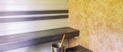 Sauna, jossa on puiset lauteet ja kiviseinä.