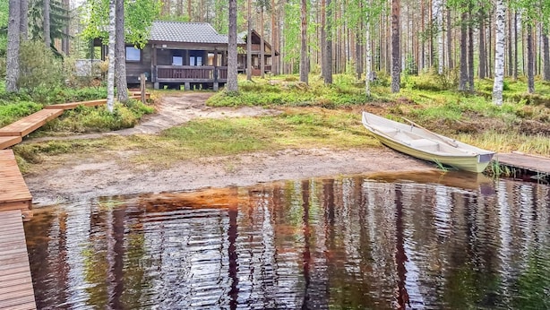 A cabin in a forest with a wooden dock and a boat. - Pilkkaniemi by Interhome (Juuka)