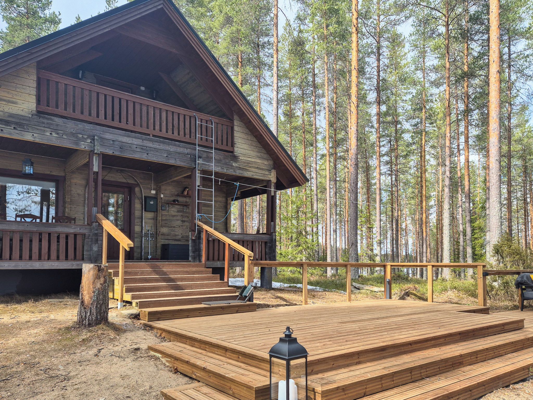 En stuga med en träveranda, en trappa och utsikt över en skog.