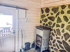 Et rustikt interiør med en stenvæg, en dør i træpaneler og en lille pejs.