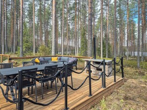 An outdoor deck with a dining area, surrounded by a forest.
